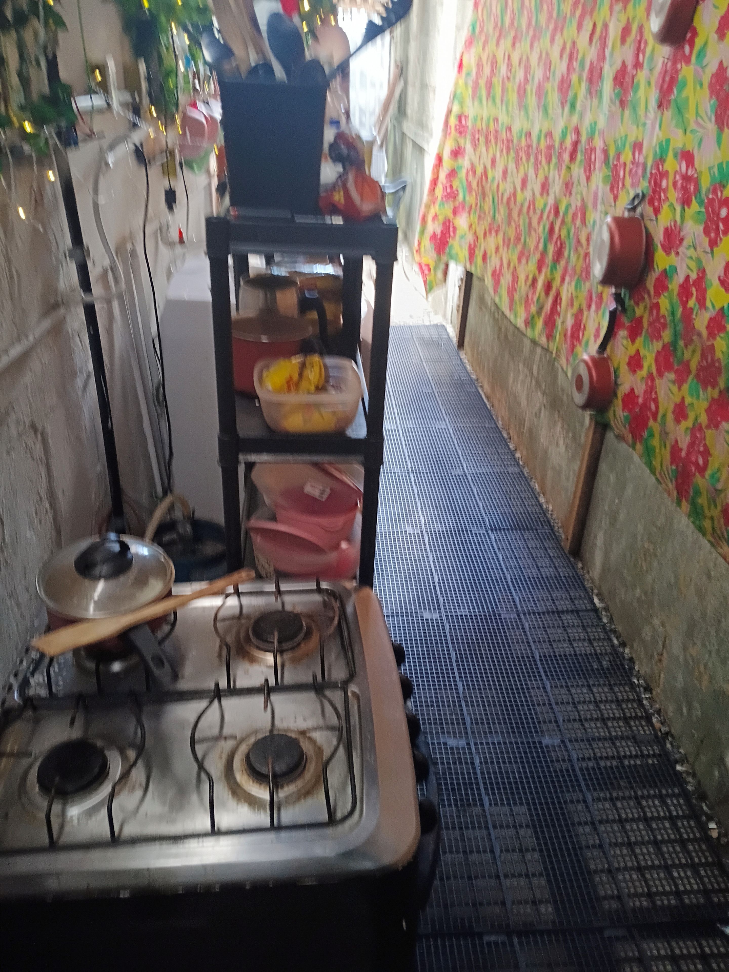 Keittiössä on kaasuliesi, hylly, jossa on ruokatarvikkeita, ja kuviollinen seinä.