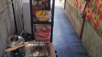 Keittiössä on kaasuliesi, hylly, jossa on ruokatarvikkeita, ja kuviollinen seinä.