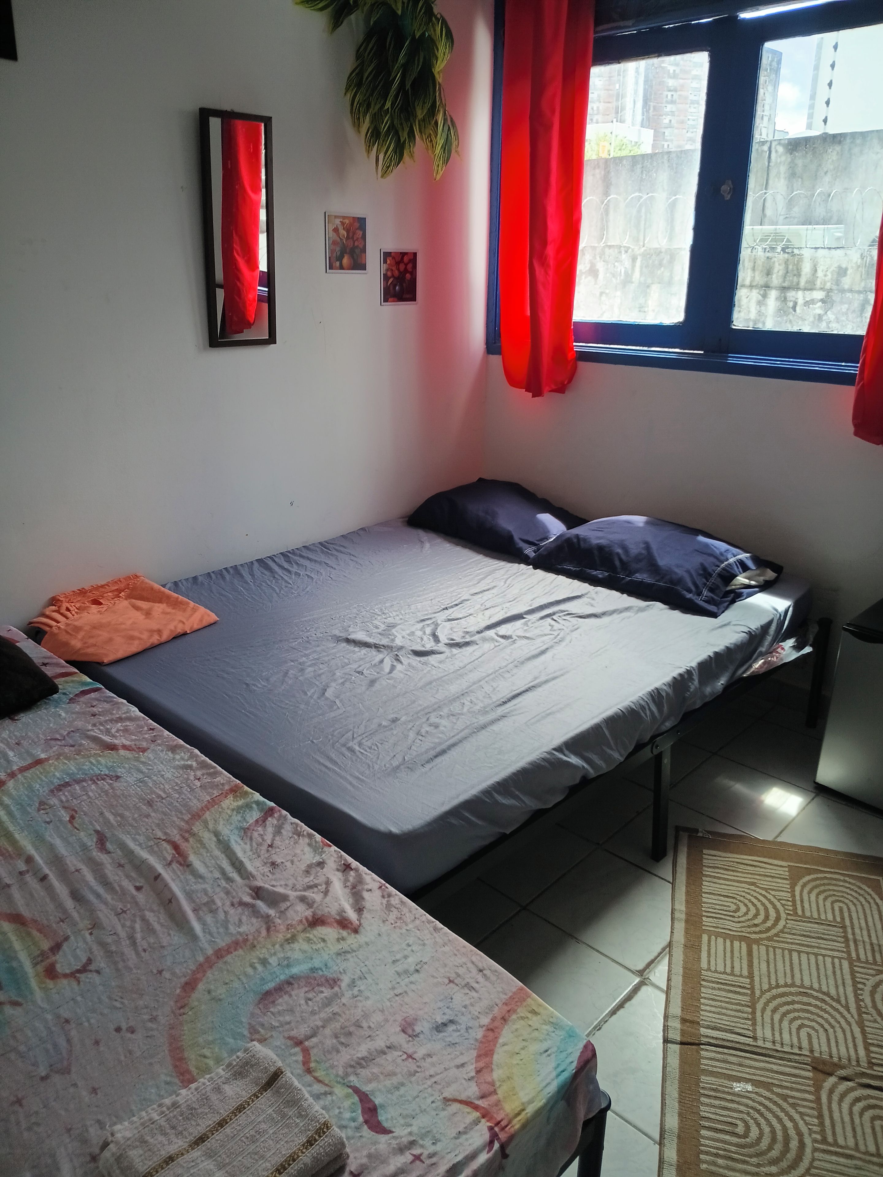 Un dormitorio con cama, una mesita y una ventana con cortinas.