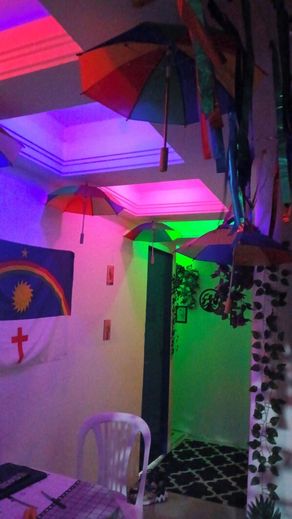 A room with a ceiling that has hanging umbrellas and a wall with a flag and a cross.