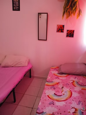 A bedroom with two beds, one with a pink blanket and the other with a rainbow-patterned blanket. - Boa Viagem Inn  (Recife)