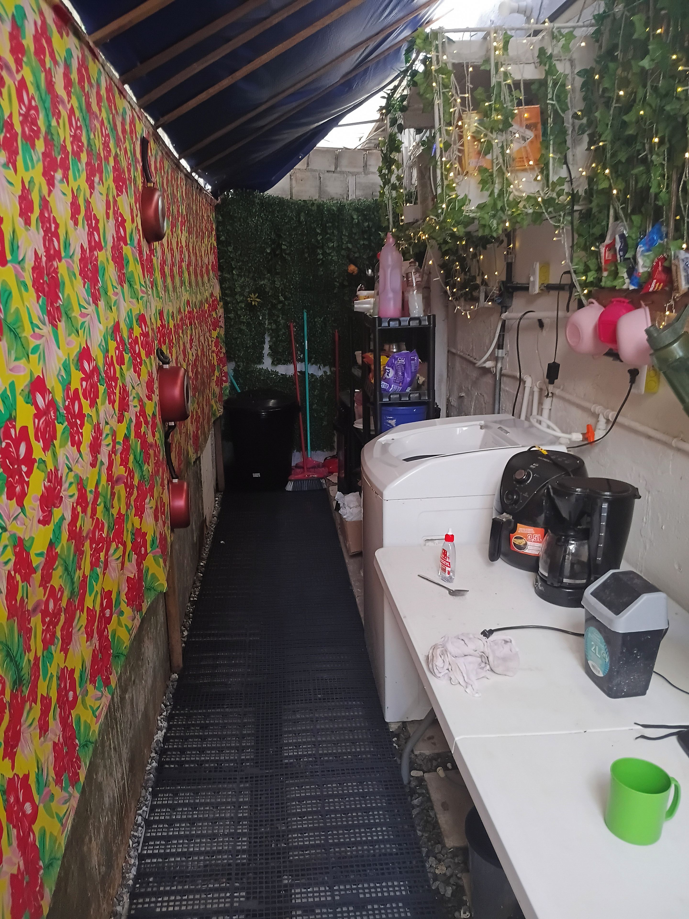 A narrow corridor with a patterned wall, a white counter with a green mug, and a coffee maker.