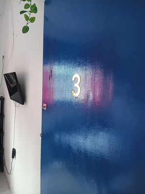 A room with a blue wall, a number '3' sign, a plant, and a speaker. - Boa Viagem Inn (Recife)