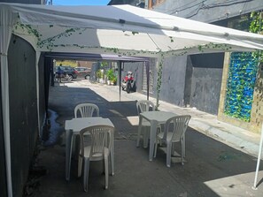 An outdoor seating area with a table and chairs under a tent.
