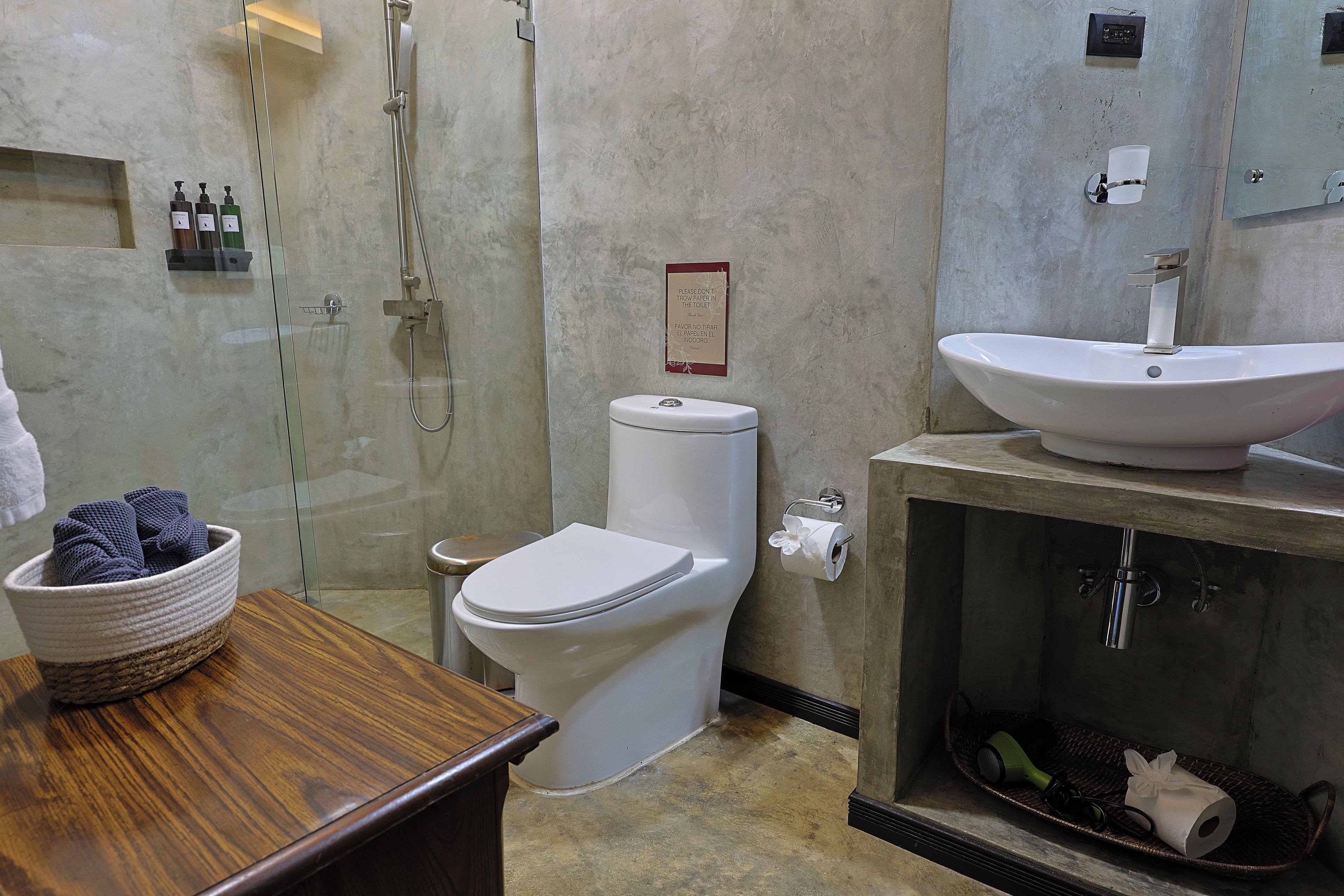A bathroom with a shower, toilet, sink, and a wooden vanity.