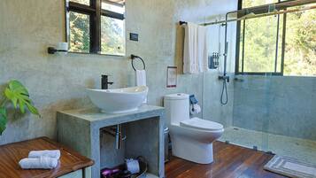A bathroom with a large window, a sink, a toilet, and a shower area.