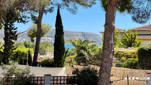 Zona residencial con árboles, un muro de piedra y vistas a una montaña distante.