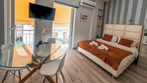 Een moderne hotelkamer met een glazen eettafel, een bed met een gestreept hoofdeinde, en een airconditioningsunit.