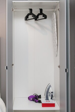 A white wardrobe with a hanging rack, a first aid kit, and a purple object on the lower shelf. - Stylish Studio Steps from the Acropolis- Cielo Homes (Athina)