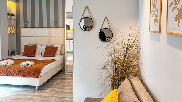 Een moderne slaapkamer met een bed, nachtkastjes, een bank en een wandmeubel.