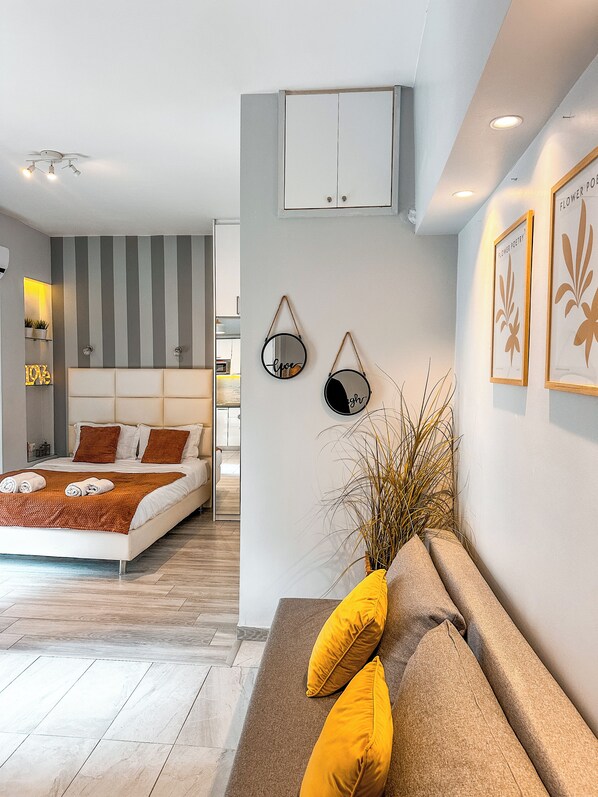 A modern bedroom with a bed, bedside tables, a sofa, and a wall-mounted cabinet. - Stylish Studio Steps from the Acropolis- Cielo Homes (Athina)