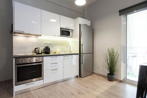 A modern kitchen with white cabinets, stainless steel appliances, a microwave, and a refrigerator. - Stylish Studio Steps from the Acropolis- Cielo Homes (Athina)