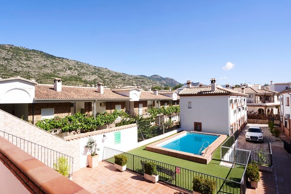 A residential area with a swimming pool, a white car, and a mountain in the background.