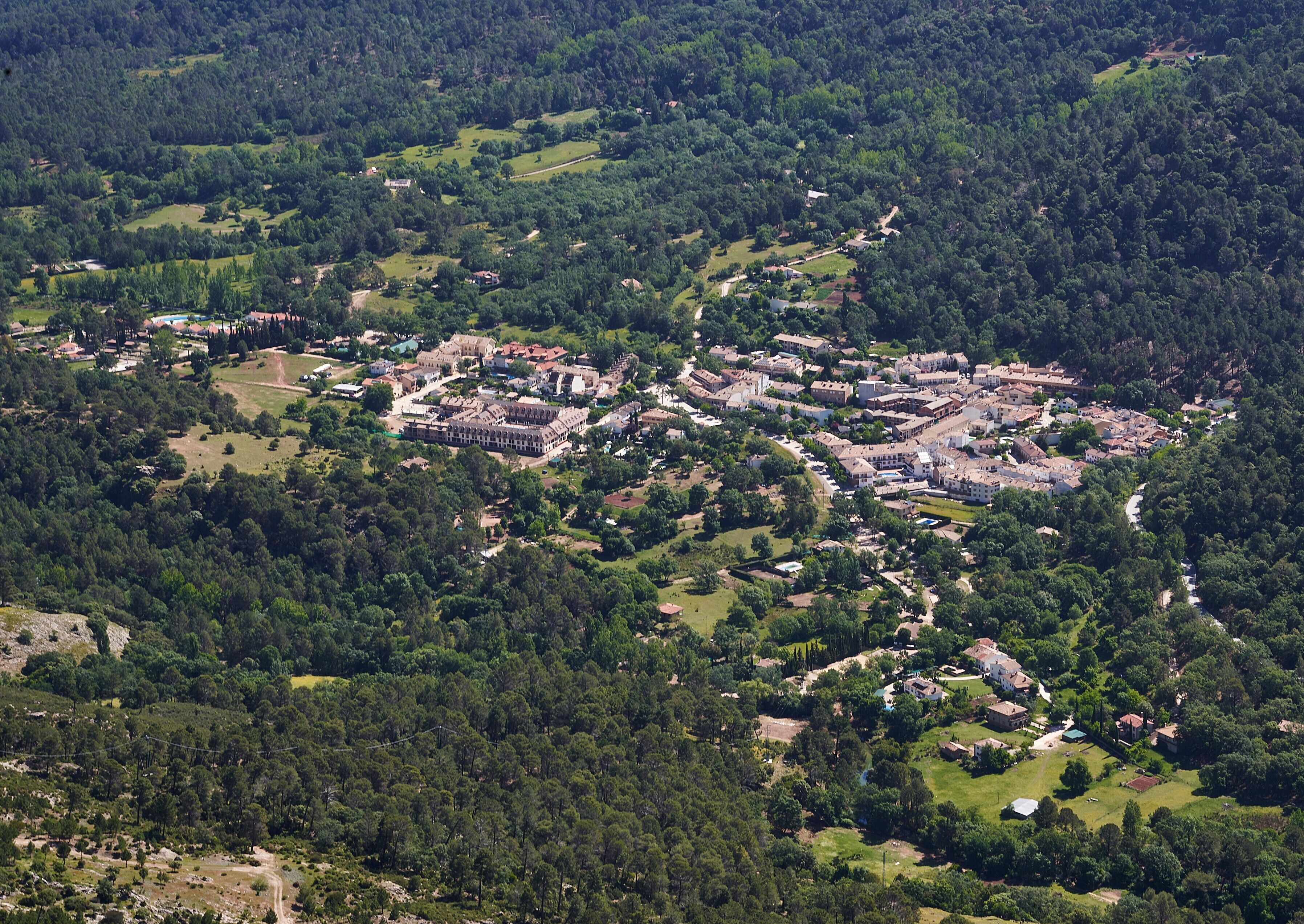An aerial view of a historic town with a central castle-like structure surrounded by residential buildings and green spaces.