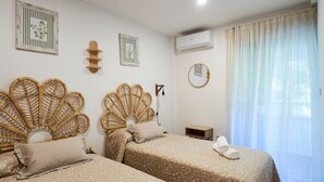 A bedroom with two beds, a wall-mounted air conditioner, and a window with sheer curtains. - Apartment 'Estrella Del Guadalquivir' with Shared Pool, Wi-Fi and Air Conditioning (Arroyo Frio)