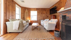Una sala de estar acogedora con paredes de madera, una chimenea, un televisor y un sofá.
