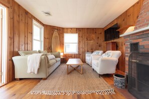 Ein gemütliches Wohnzimmer mit Holzwänden, einem Kamin, einem Fernseher und einem Sofa.