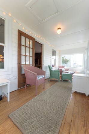 Ein Zimmer mit Holzboden, einem großen Fenster und einer Glastür.
