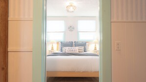 Un dormitorio con una cama, dos lámparas de noche, un reloj de pared y una ventana con persianas.