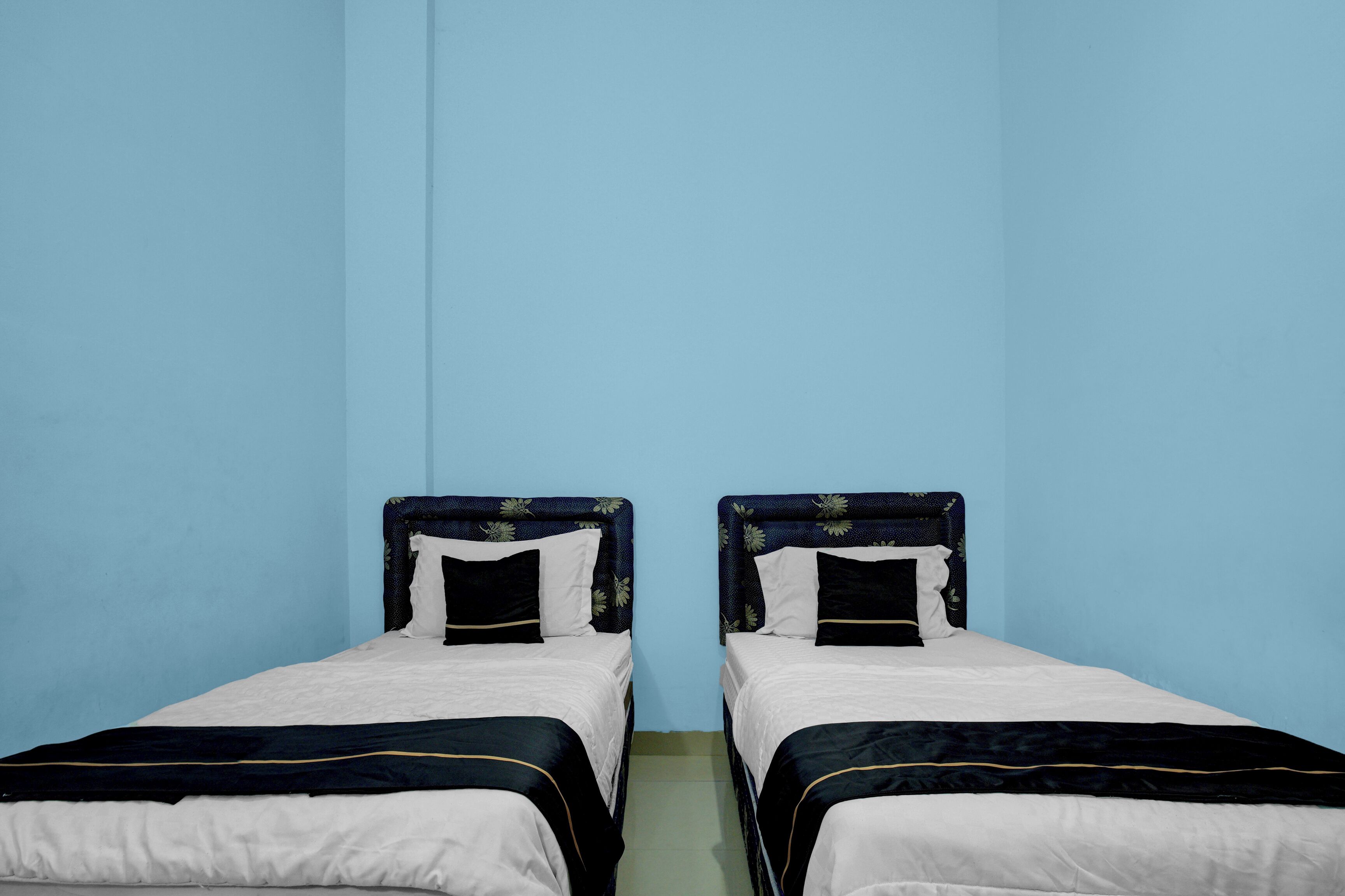 Due letti singoli con testiere, una parete blu e un pavimento verde.