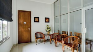 A room with a wooden door, a dining table with chairs, a vase with flowers, and a large glass door. - Hotel O near Palembang Square Mall formerly Wisma Faeyza Syakira (Palembang)
