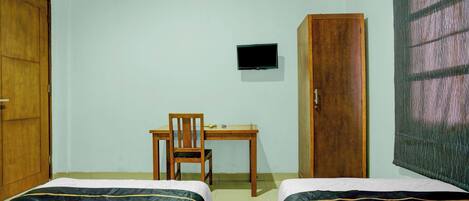 A room with two beds, a desk, a chair, a television, and a wardrobe.