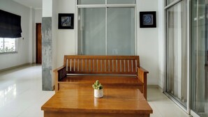 A wooden bench with a potted plant in the center, a glass door, and a framed picture on the wall. - Hotel O near Palembang Square Mall formerly Wisma Faeyza Syakira (Palembang)