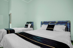 Dos camas individuales con cabeceras, ropa blanca de cama y una manta azul oscuro.
