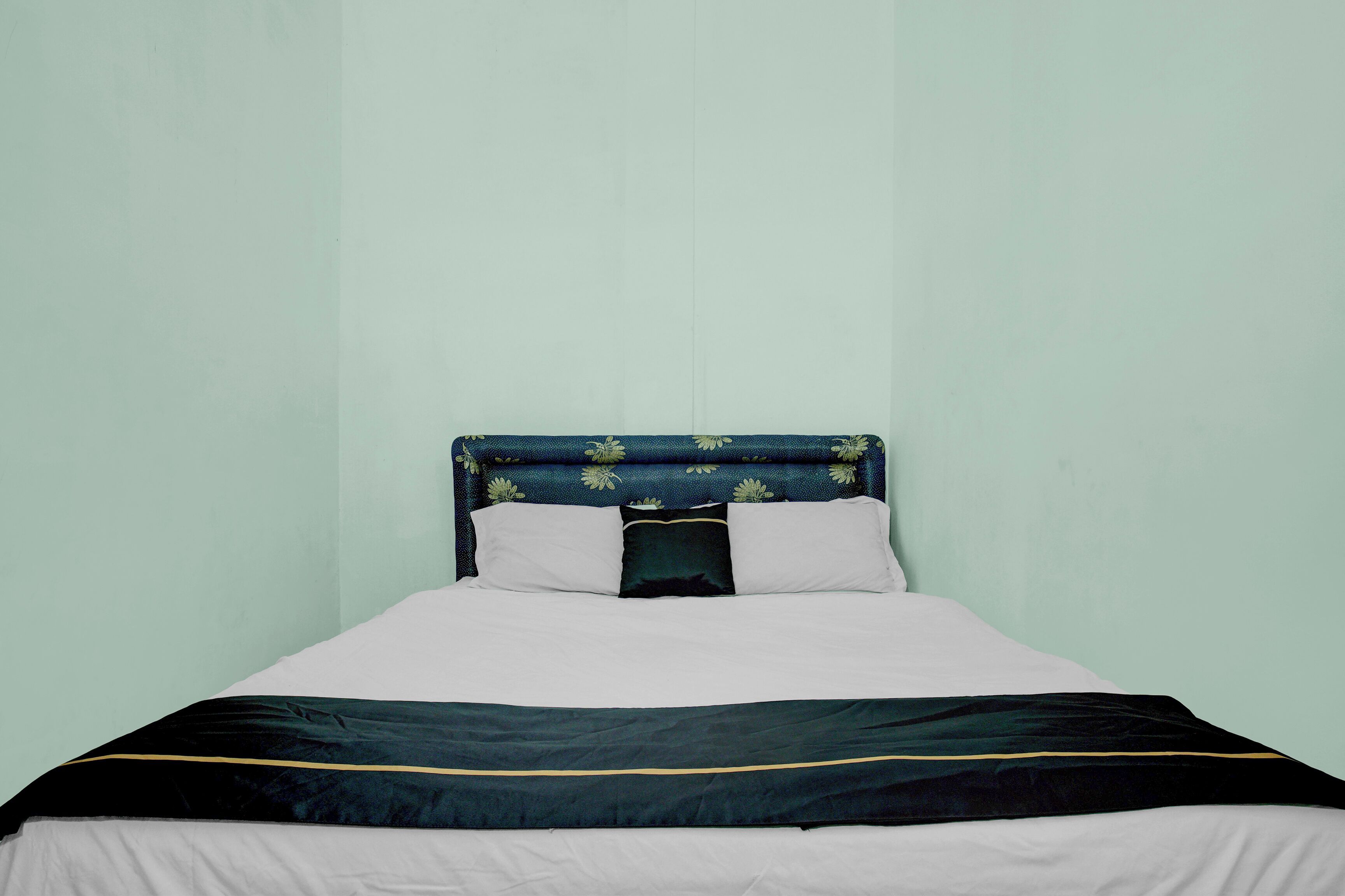 A bed with a headboard, two pillows, and a bedspread.