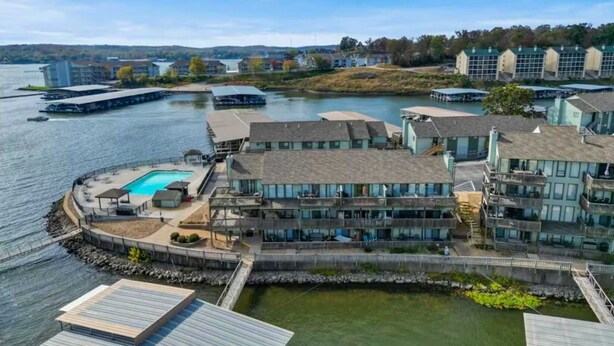 Un hotel frente al agua con piscina, varios balcones y un muelle.