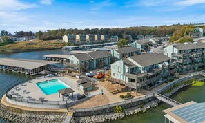 A waterfront hotel with a pool, multiple buildings, and a dock. - Charming 1BR Condo - Top Floor - LAKE VIEW (Village of Four Seasons)