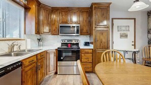 A kitchen with wooden cabinets, a stainless steel microwave, a stove, and a dishwasher. - Charming 2BR Condo - LAKE VIEW - Osage Beach (Osage Beach)