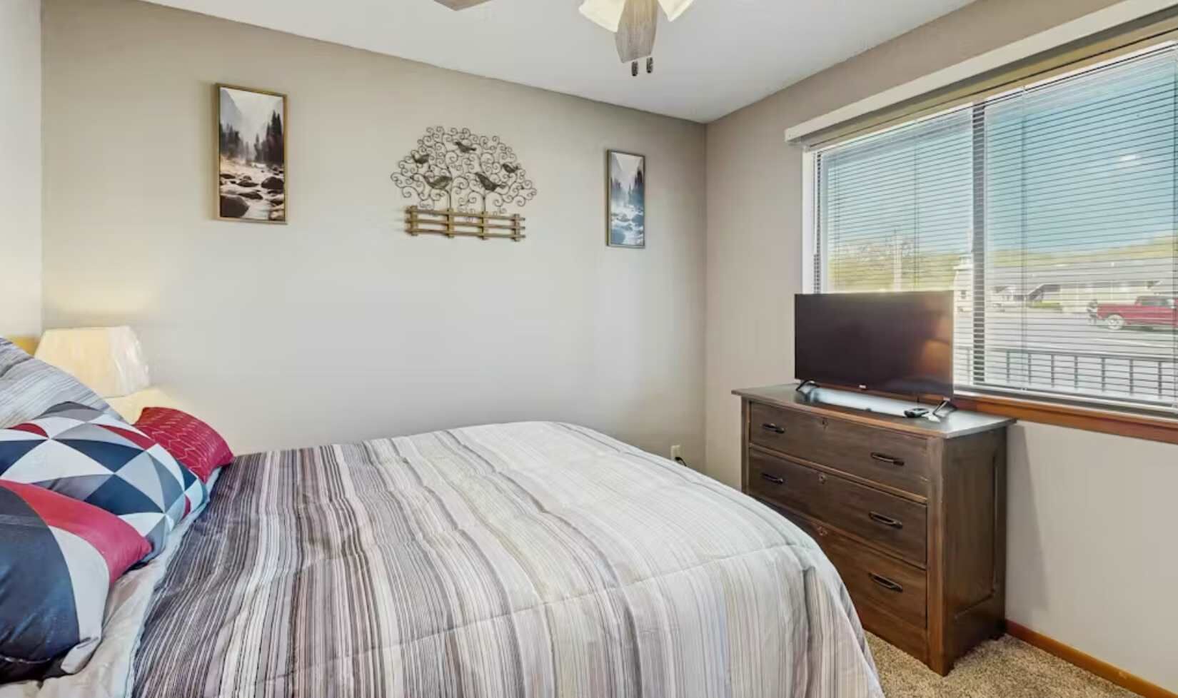 Ein Schlafzimmer mit einem Bett, einem Schminktisch, einem Fernseher und Bildern an der Wand.