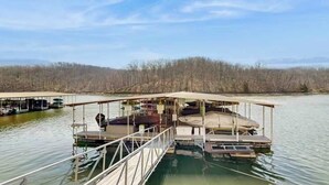 A floating structure with a covered deck, a dock, and a boat. - Charming 2BR Condo - LAKE VIEW - Osage Beach (Osage Beach)