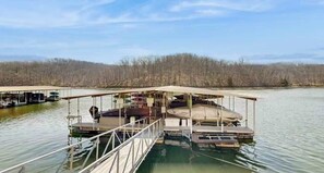 Eine schwimmende Plattform mit einer überdachten Terrasse, einem Steg und einem Boot.
