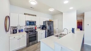 Une cuisine moderne avec des meubles blancs, des appareils en acier inoxydable et un îlot central.