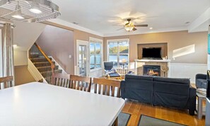 Una sala de estar moderna con chimenea, un comedor y una escalera.