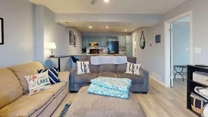 Ein Wohnzimmer mit zwei Sofas, einem Couchtisch und einer Küche im Hintergrund.