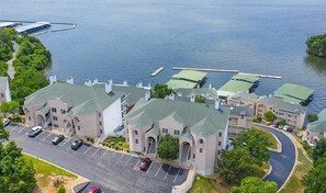 A large building with multiple wings, a parking lot, and a body of water in the background. - Bright 3BR Condo - LAKE VIEW - Lake Ozark (Lake Ozark)