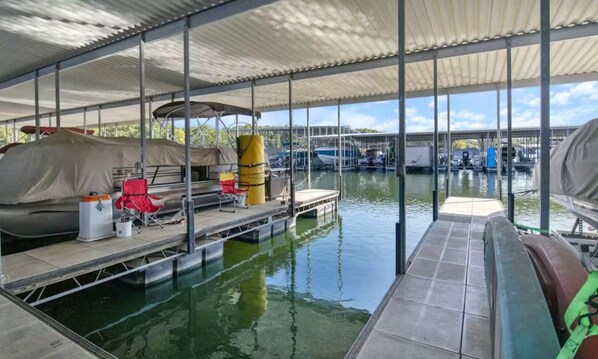 Un quai abrité avec un bateau, un espace de repos couvert et une vue sur les bateaux sur l’eau.