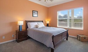 Une chambre à coucher avec un lit, des tables de chevet, une fenêtre et une horloge au mur.