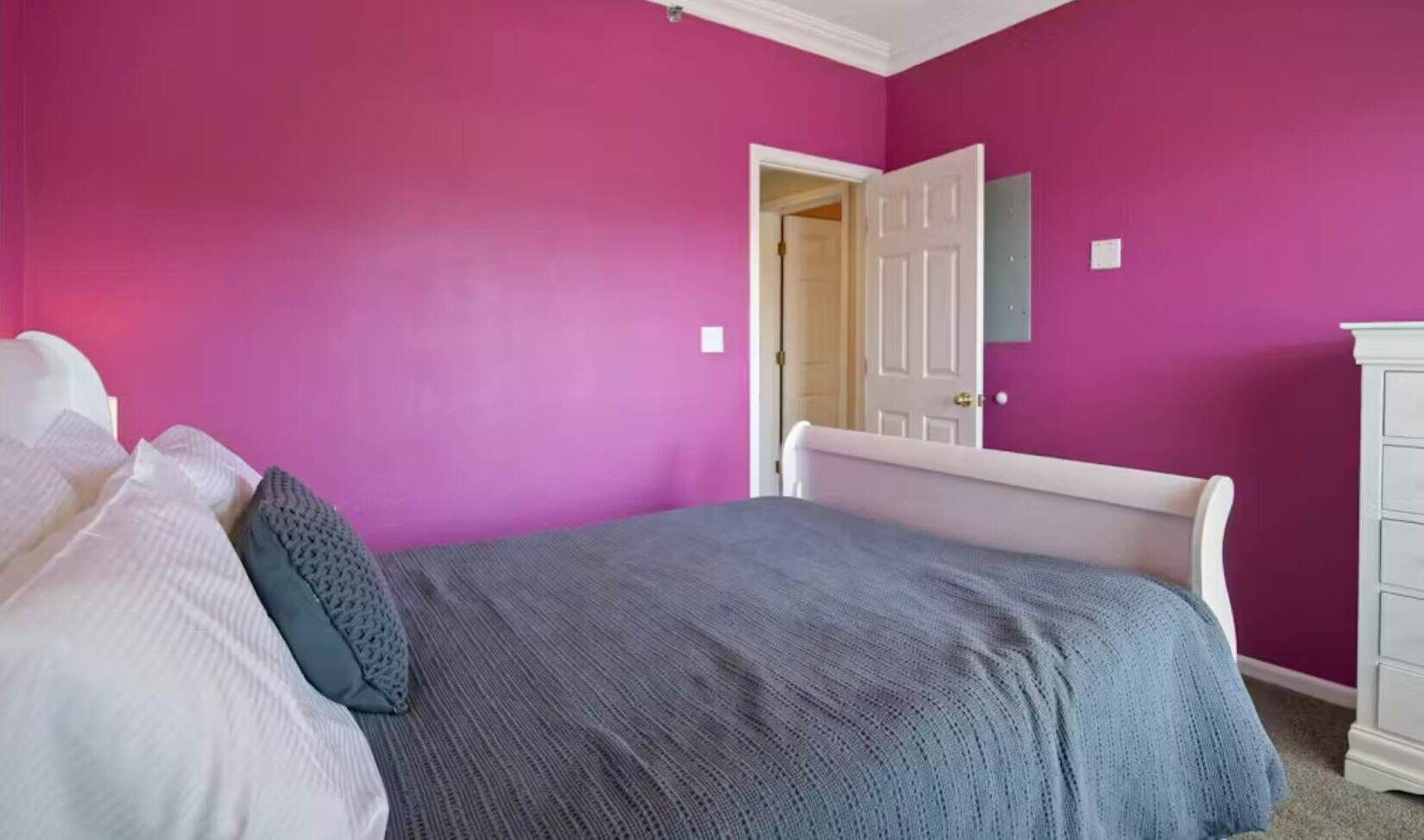 Un dormitorio con una cama, un aparador blanco y una puerta que da a otra habitación.