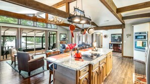 A spacious kitchen with a large island, wooden cabinets, and a dining area with a table and chairs. - Rustic 3BR Lake House - LAKE VIEW - Lake Ozark (Lake Ozark)