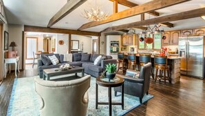 A spacious living area with a large sofa, a coffee table, and a dining area with bar stools. - Rustic 3BR Lake House - LAKE VIEW - Lake Ozark (Lake Ozark)