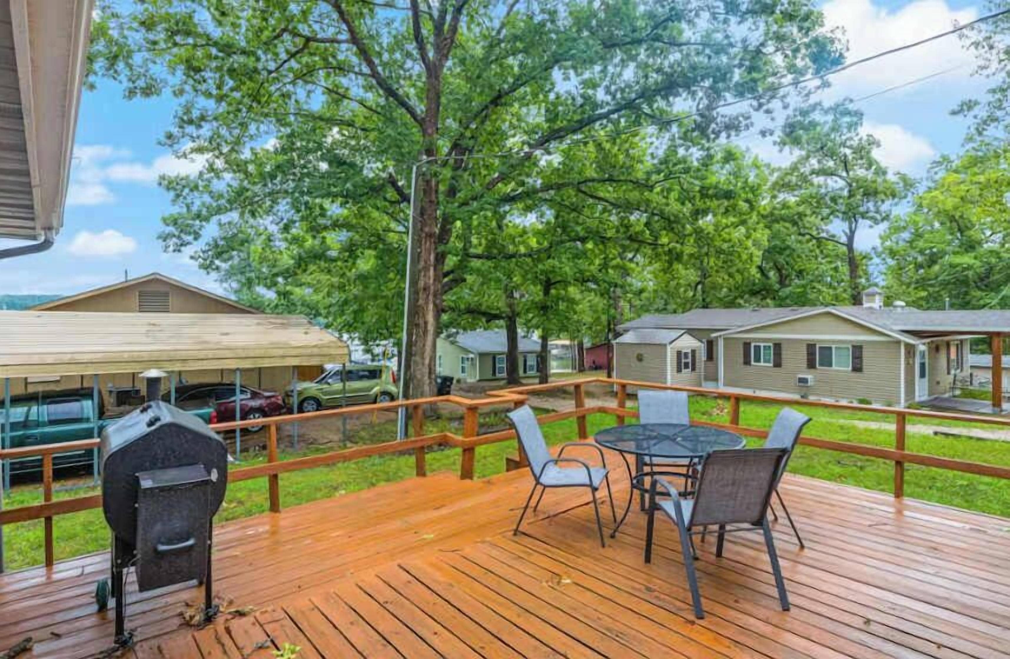 Une terrasse en bois avec un barbecue, des chaises et une table.