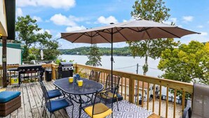 Una terraza con mesa y sillas, una parrilla y vista a un lago.