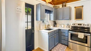 Una cocina compacta con horno empotrado, lavamanos y refrigerador.