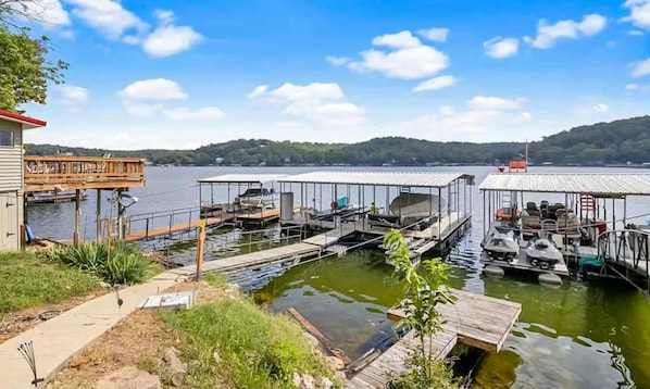 A dock with multiple boat slips, a covered area, and a building with a deck.