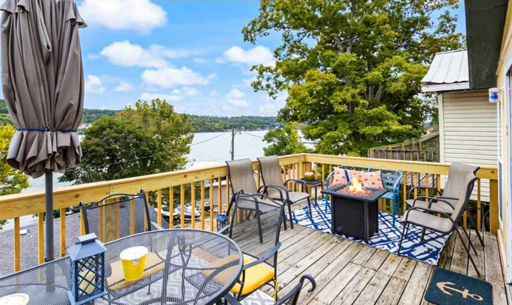 A deck with outdoor furniture, a fire pit, and a view of a lake.