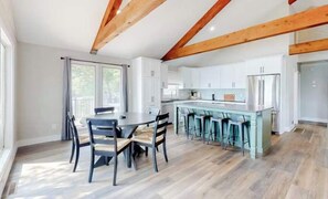 A modern kitchen with white cabinets, a central island with bar stools, and exposed wooden beams on the ceiling. - Spacious 4BR Lake House - LAKE VIEW - Rocky Mount (Rocky Mount)
